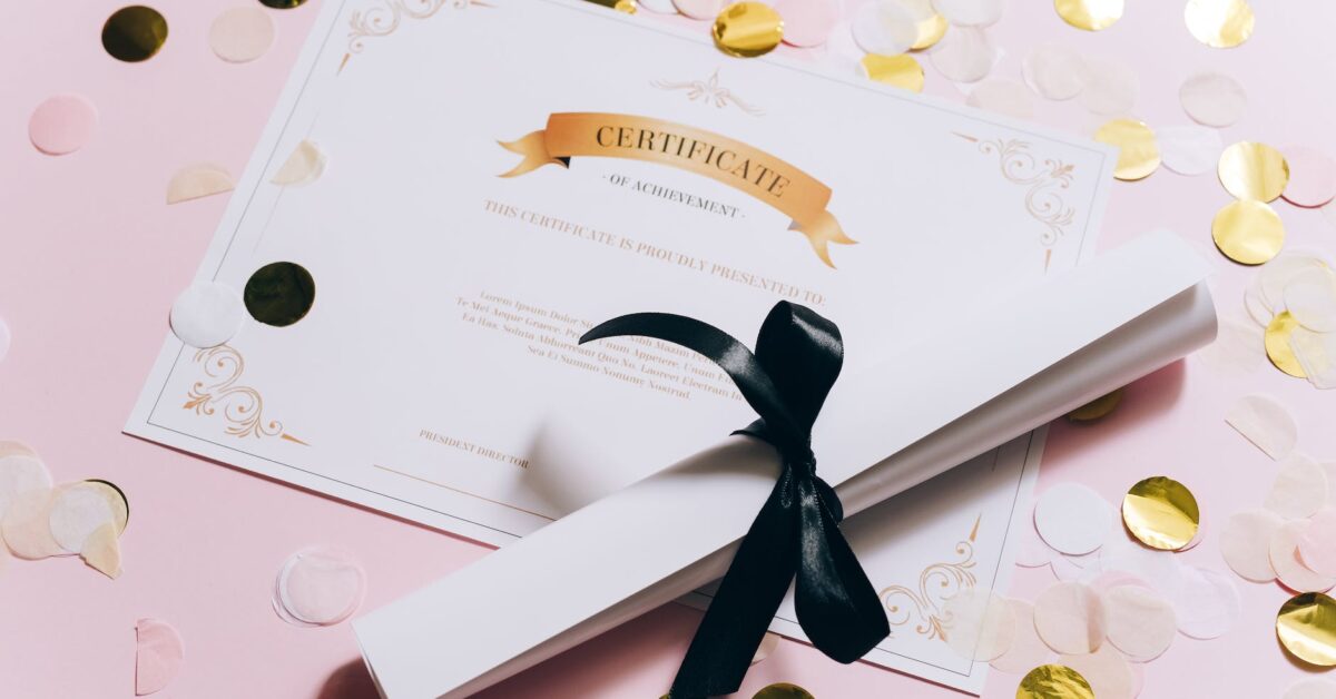 rolled white paper and a certificate on a pink surface